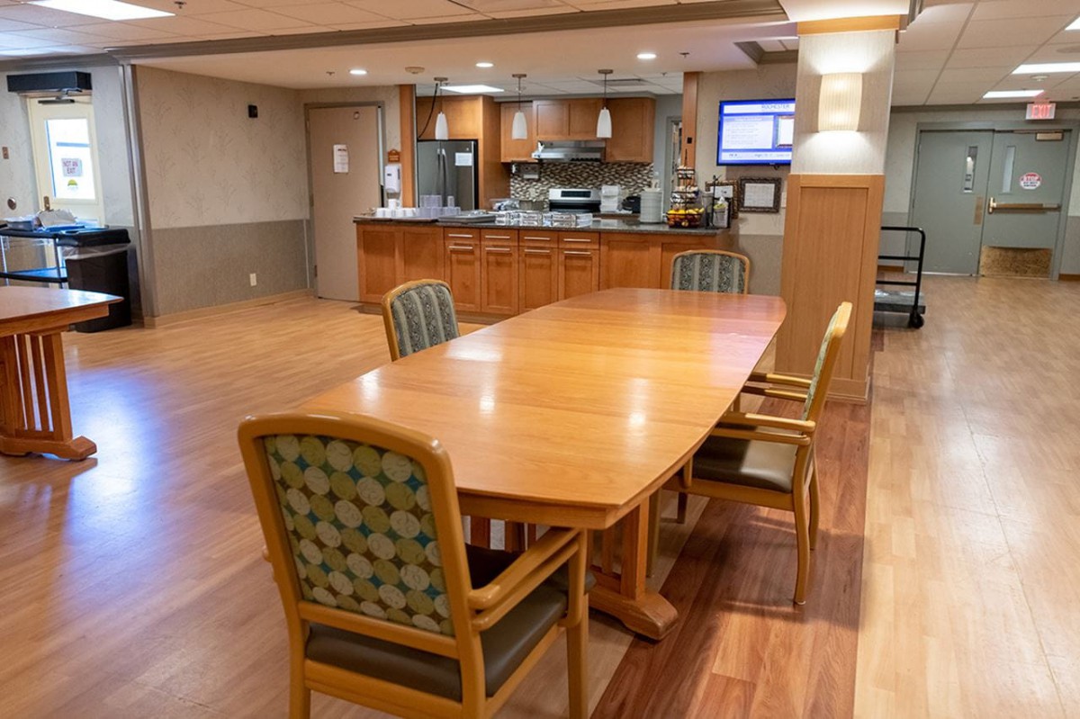 A spacious kitchen and dining area with wooden flooring, featuring a large table and chairs.