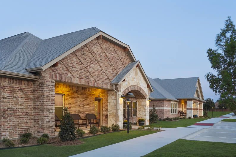 A suburban brick building with a well-maintained lawn and driveway.