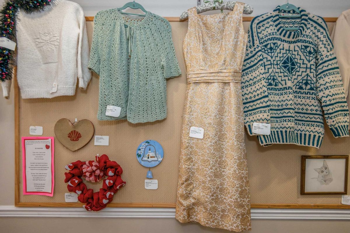 A display featuring a variety of garments, including sweaters and a dress, along with decorative items.