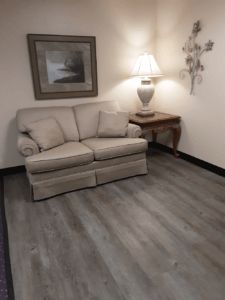 A cozy living room corner with a beige sofa, side table, and lamp.