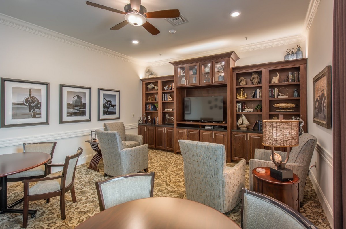 A cozy living room with armchairs, a television, and built-in bookshelves filled with decorative items.
