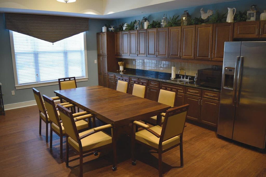 A dining room with a wooden table and chairs, surrounded by cabinets.