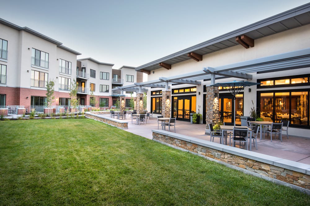A modern apartment complex with well-maintained landscaping and outdoor seating areas.