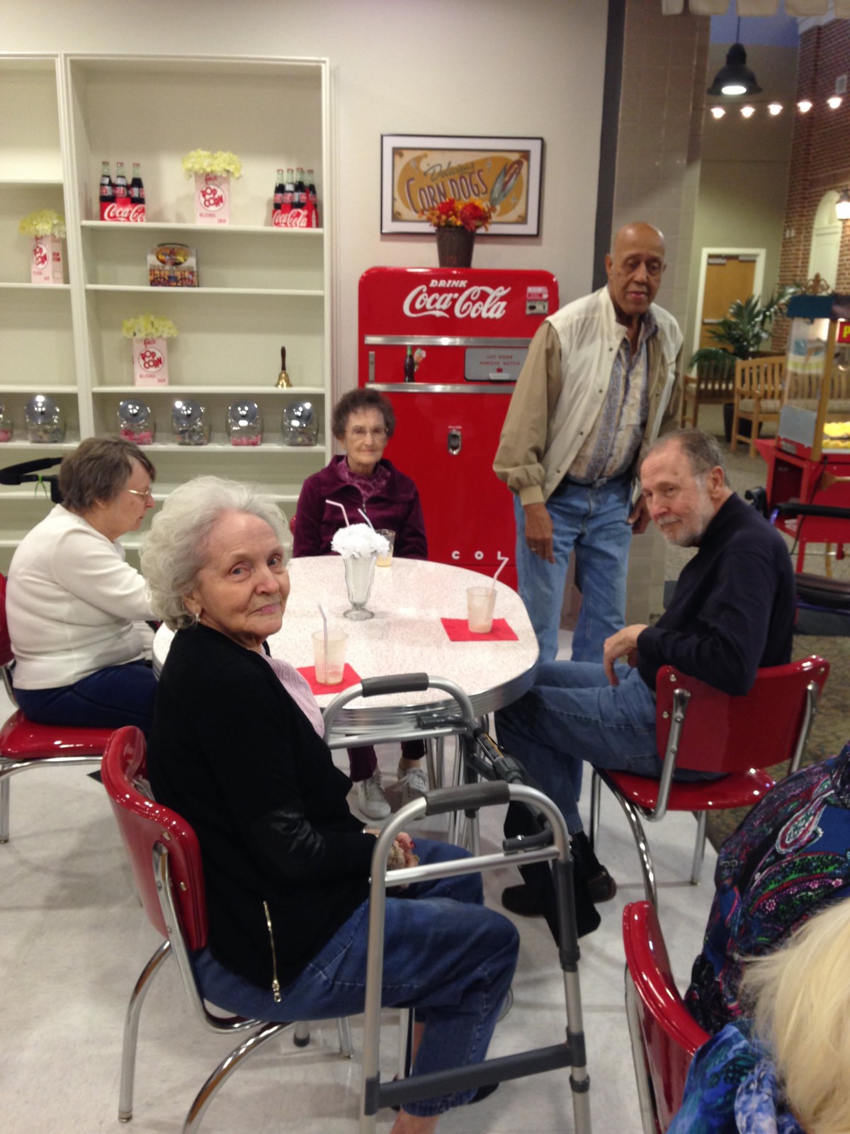 A group of seniors enjoying a gathering in a cafe with vintage Coca-Cola decor.