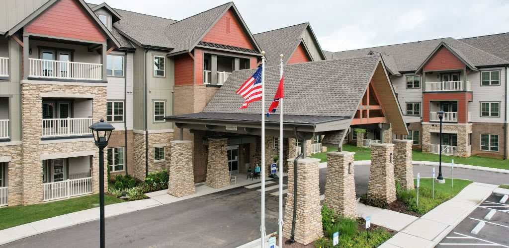 The image shows the entrance of a building with stone pillars and flags displayed in front.