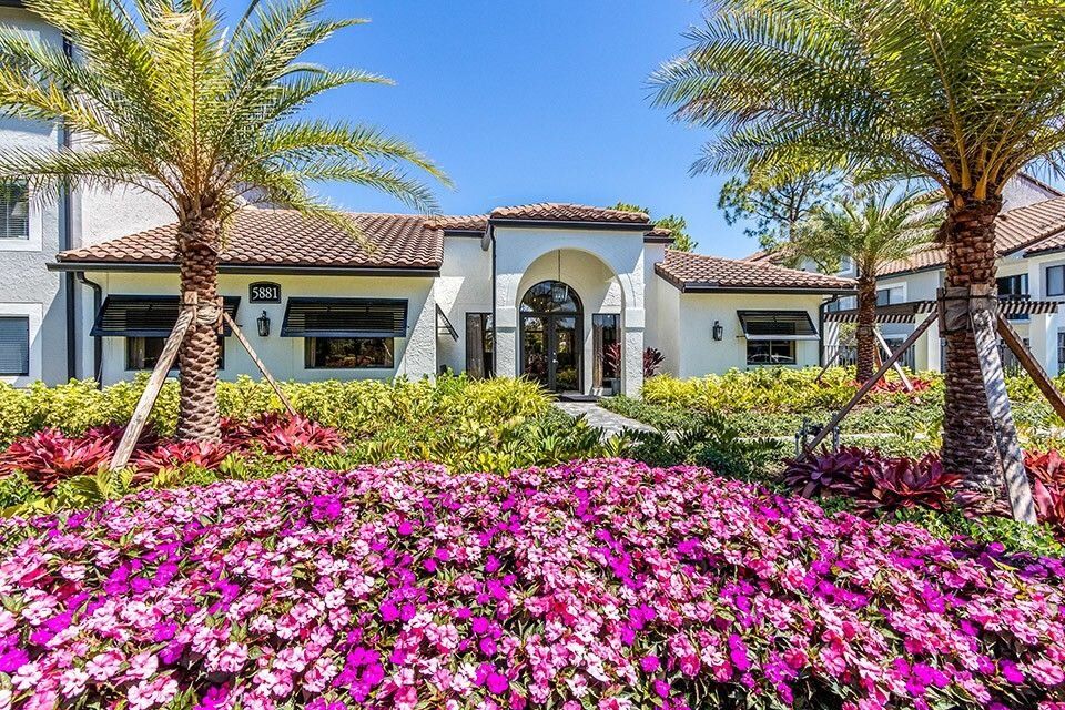 A beautiful house with vibrant flowers and lush palm trees in the garden.