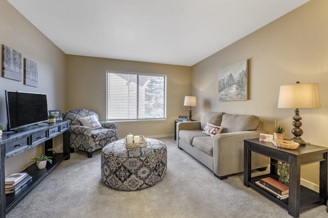 A cozy living room with a sofa, armchair, and patterned coffee table.