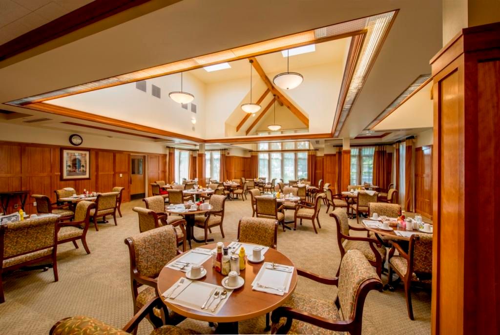 A well-lit dining room with neatly arranged tables and chairs.