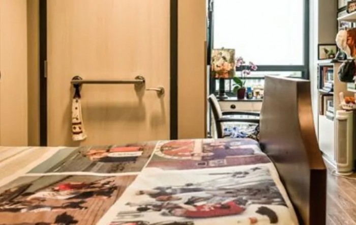 A room with a newspaper spread out on a table and a wheelchair near the door.