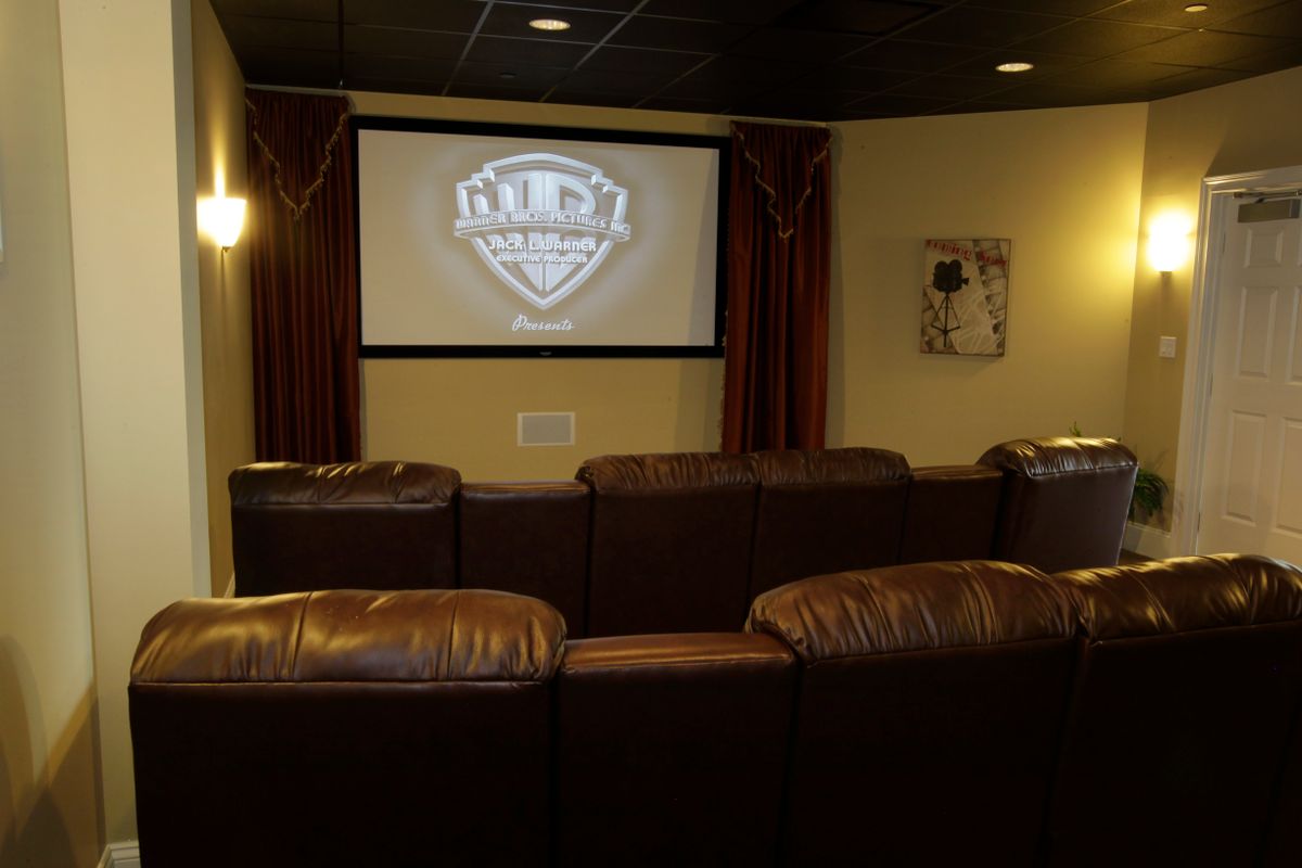 A cozy home theater setup with leather seating and a large projector screen.