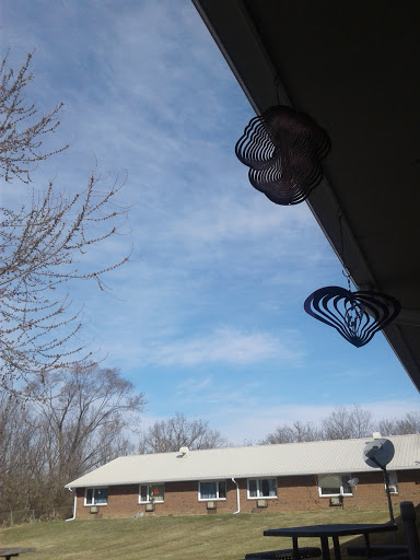 A clear blue sky with some scattered clouds, featuring hanging decorations near the roof.