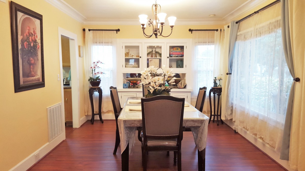 A cozy dining room with a table set for four, elegant chairs, and a chandelier overhead.