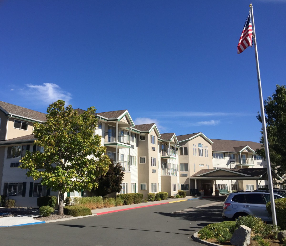 A residential apartment complex with an American flag and a clear blue sky.