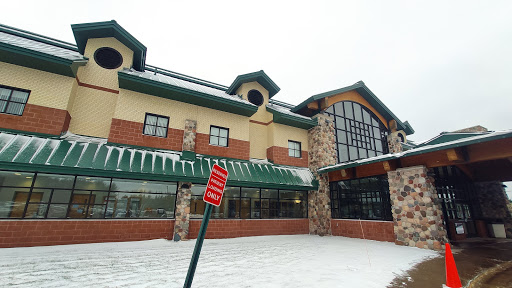 A modern commercial building covered in snow, featuring large windows and a distinctive architectural style.