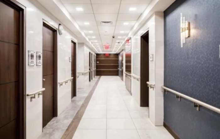 A modern hospital hallway with multiple doors and bright lighting.