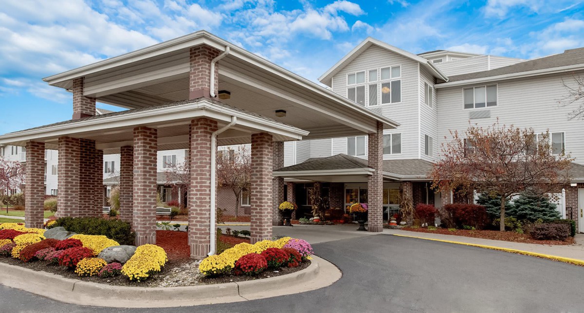 A large building with a covered entrance and surrounding landscaping.