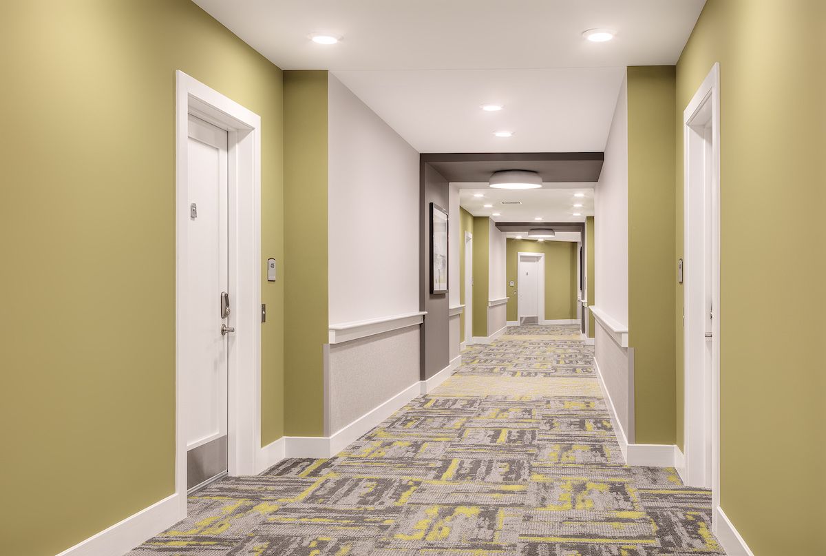 A modern hallway with soft lighting and patterned carpet.