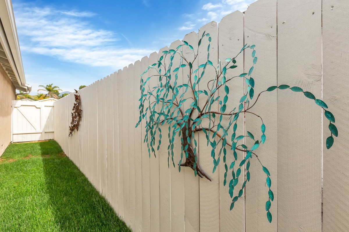 Decorative metal tree art mounted on a wooden fence.