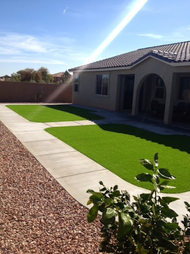 A well-maintained yard featuring artificial grass and a paved pathway leading to the house.