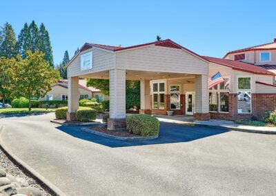 The exterior view of a hotel entrance with surrounding landscaping.