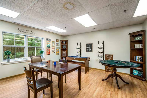 A cozy game room featuring a table, chairs, and various artworks on display.