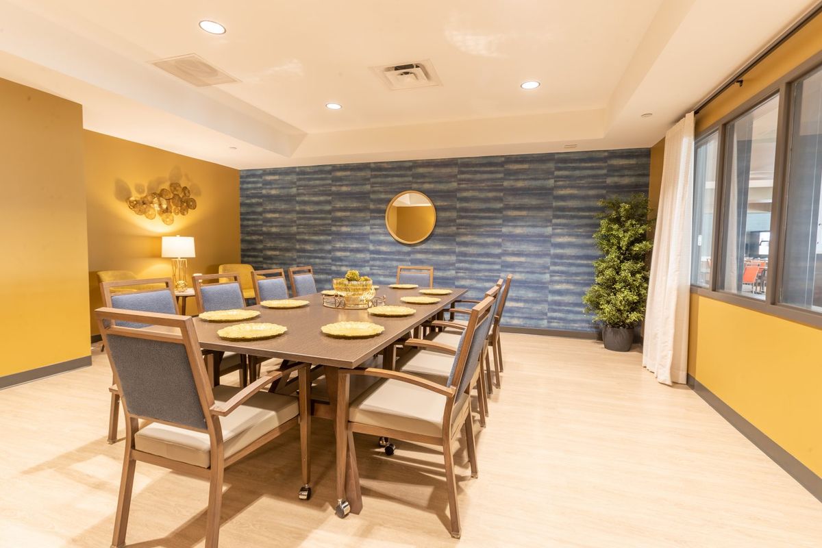 A modern dining room with a long table and chairs, featuring elegant lighting and decor.