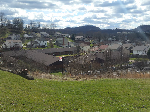 A scenic view of a town nestled among the hills, with a mix of residential homes and greenery under a cloudy sky.