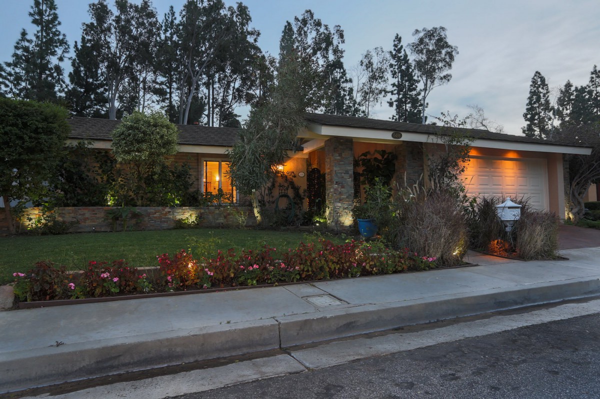 A cozy residential house with well-maintained landscaping and lit windows during the evening.