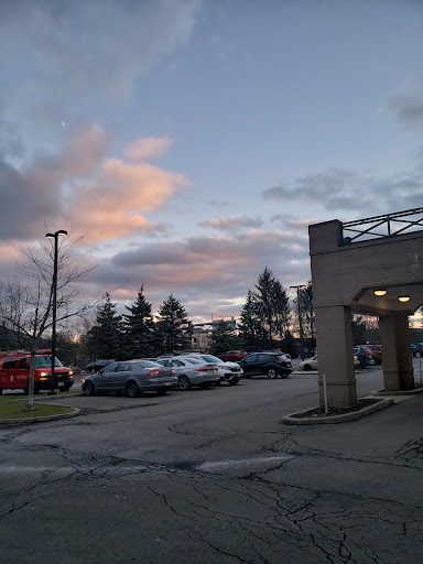 A tranquil evening scene in a parking lot, with colorful clouds framing the sunset.