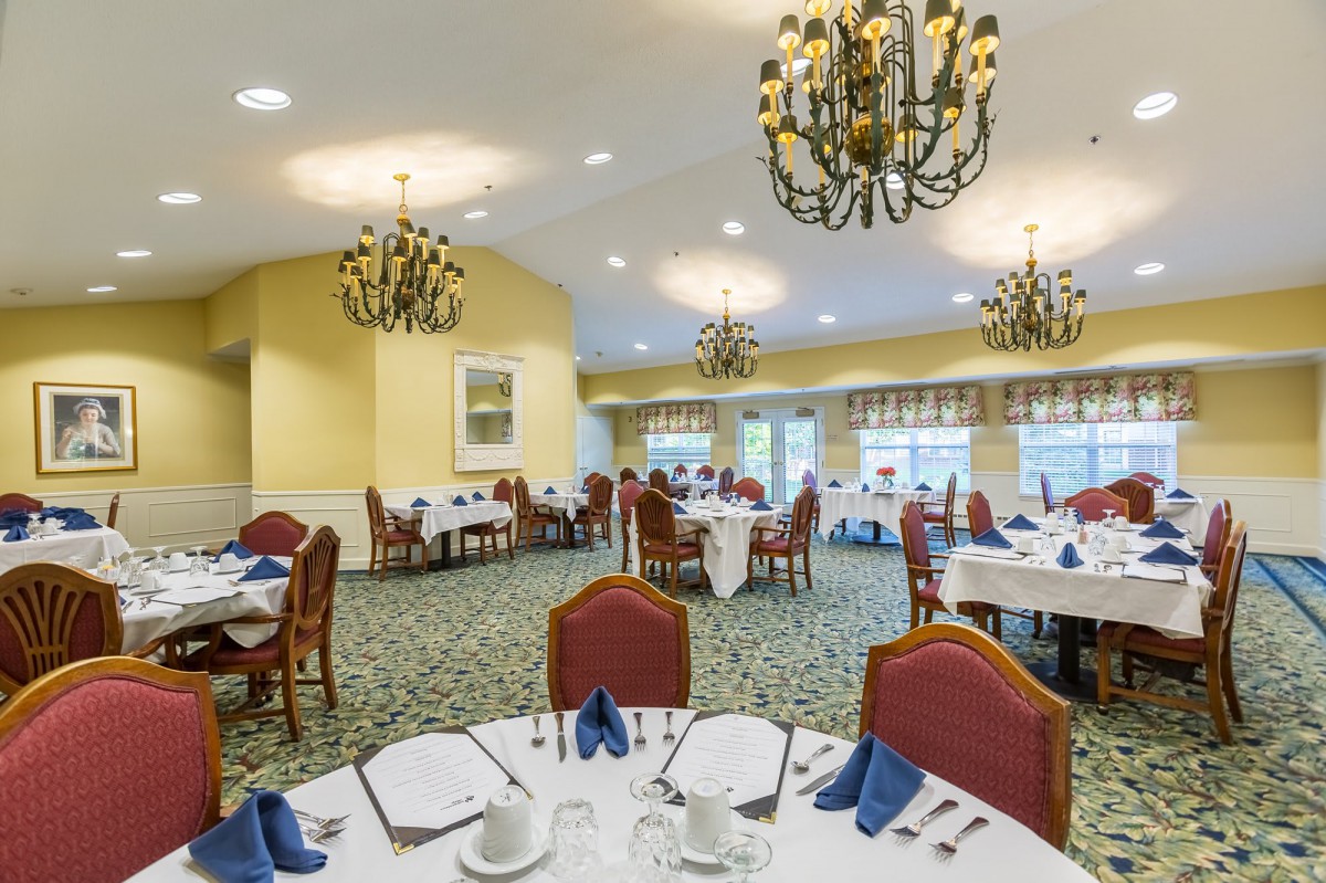 An elegant dining room with chandelier lighting and neatly set tables.