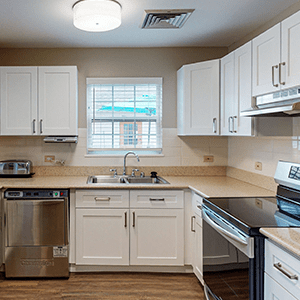 A modern kitchen with white cabinets and stainless steel appliances.