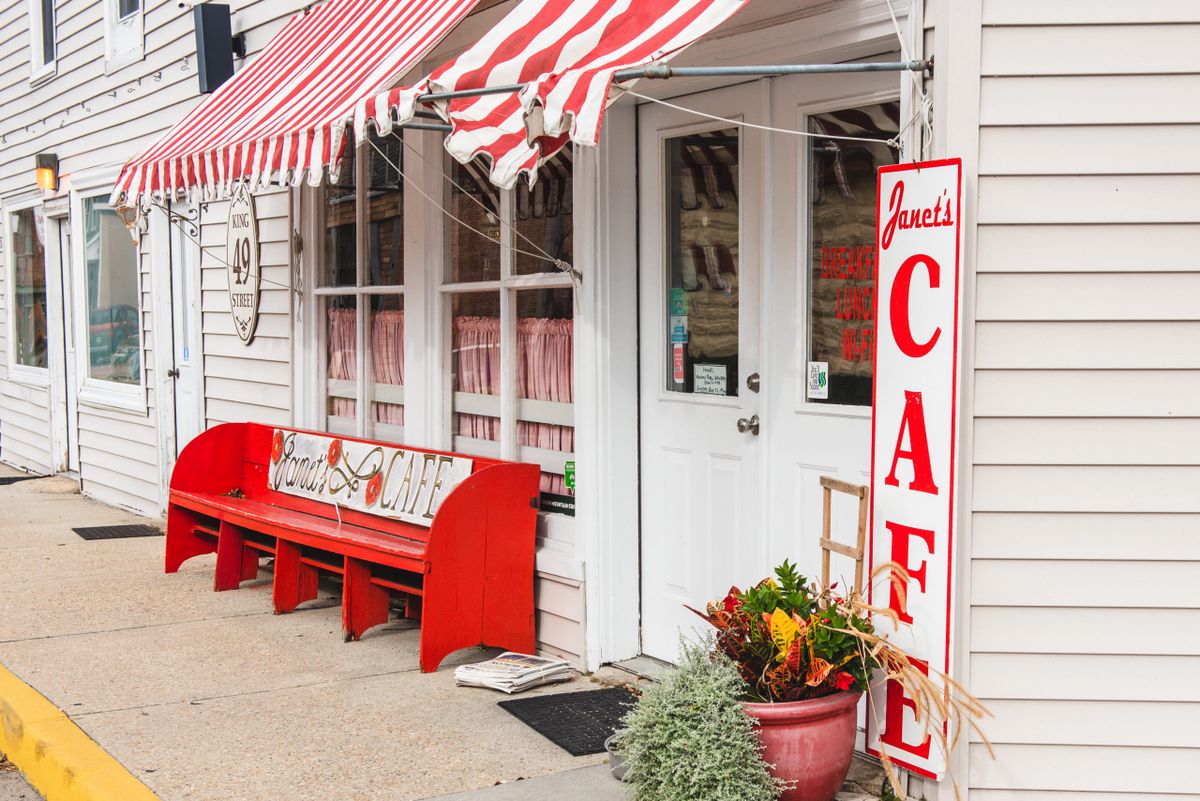 Charming cafe with a red and white striped awning and outdoor seating.