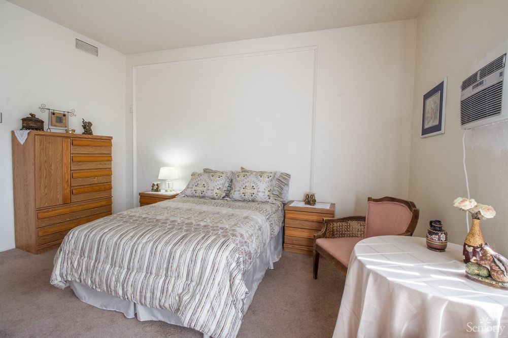 A cozy bedroom with a striped bedding set, wooden furniture, and soft lighting.