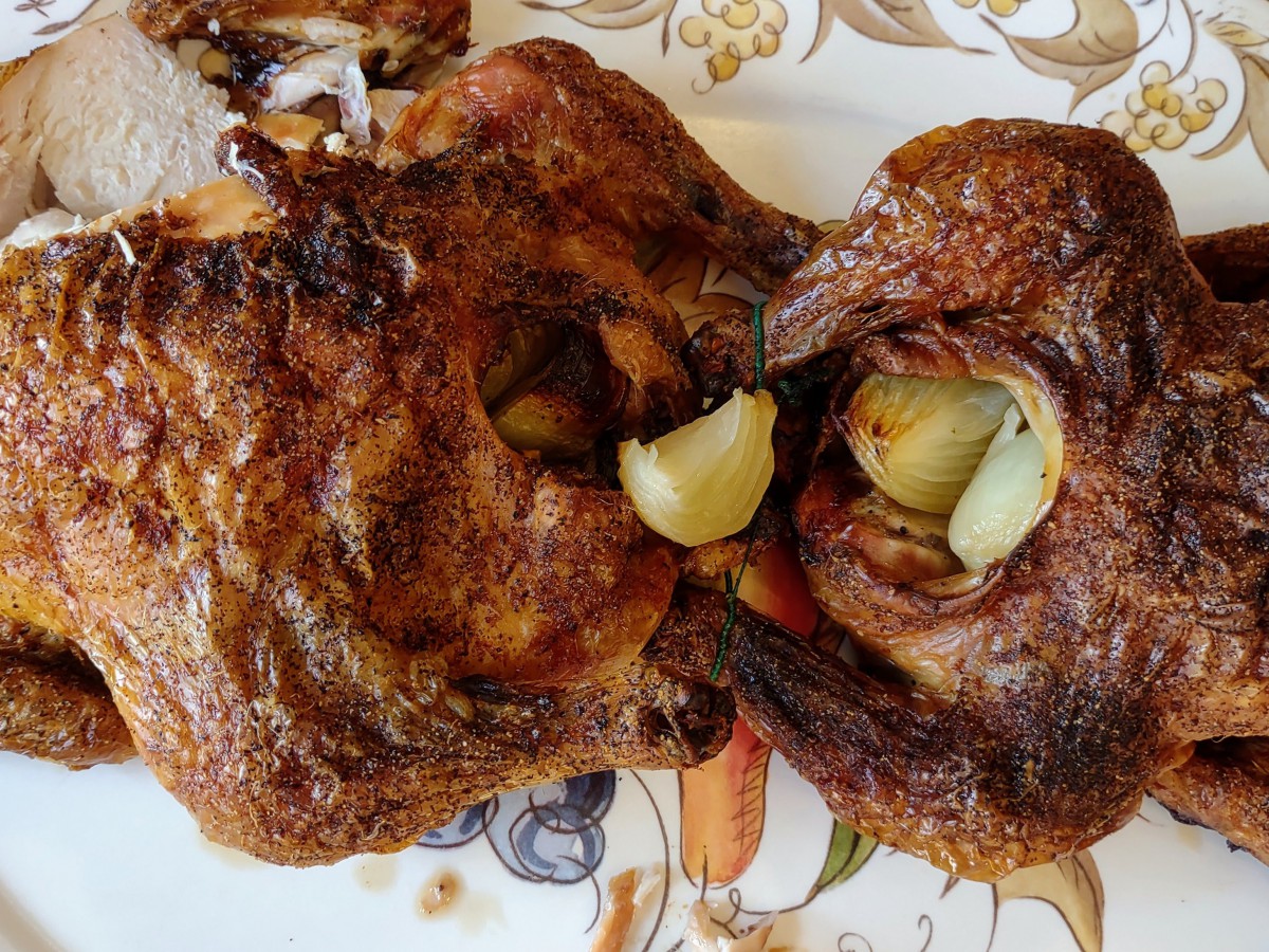 Roasted chicken with garlic cloves served on a decorative plate.