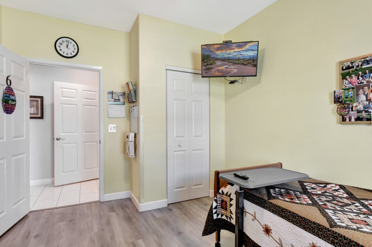 A room with a mounted television, clock, and storage area.
