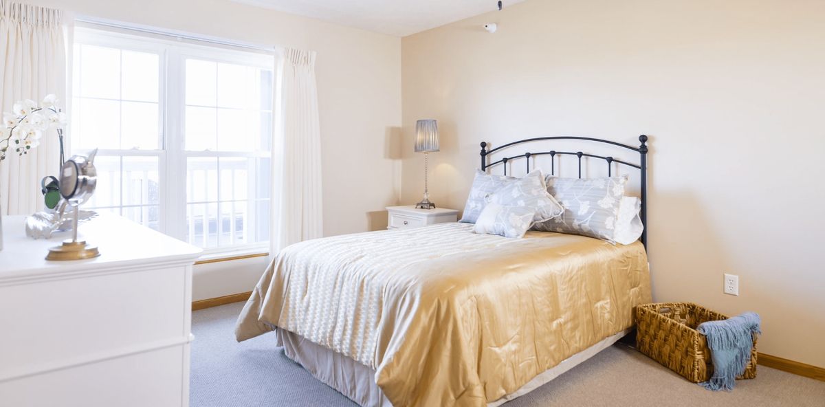 A well-lit bedroom with a metal-framed bed and neutral decor.