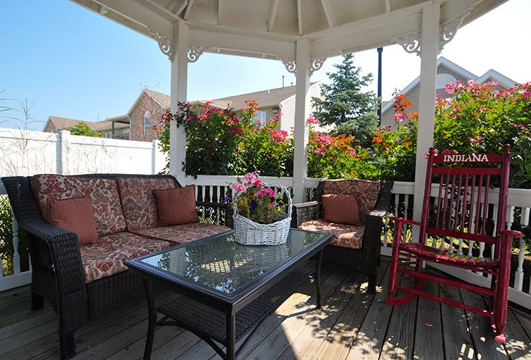 A cozy gazebo with comfortable seating and vibrant flowers, perfect for outdoor relaxation.