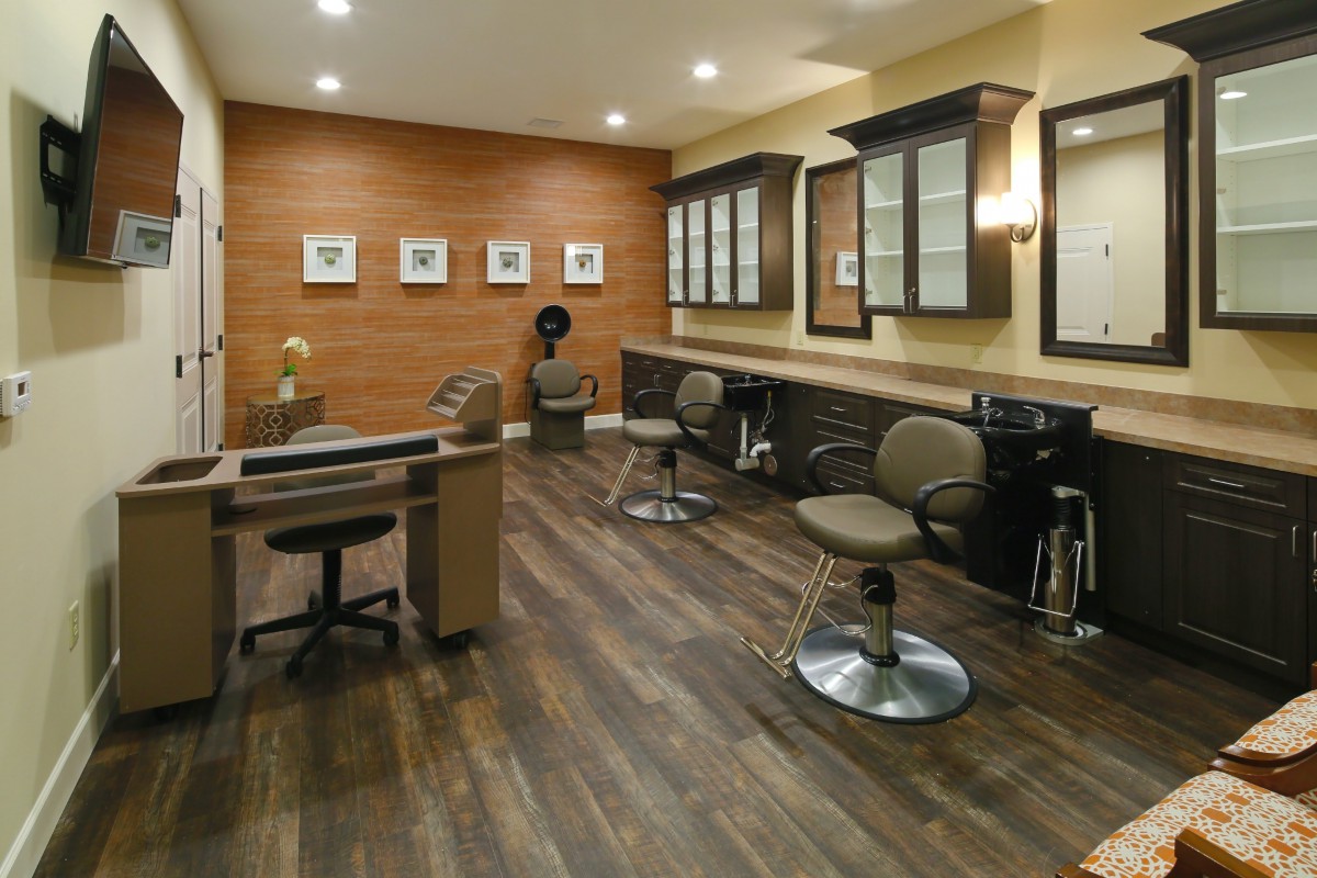 An empty salon with modern interior design, featuring mirrors, chairs, and wooden flooring.