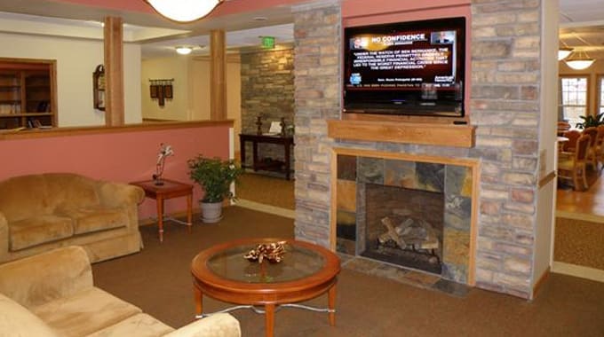 A cozy living room featuring a fireplace, television, and a coffee table with decorative items.