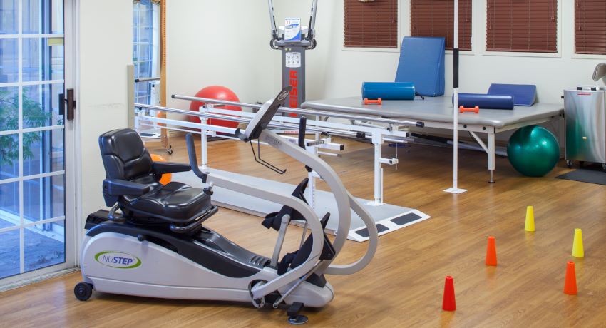 A rehabilitation room equipped with various physical therapy machines and exercise equipment.