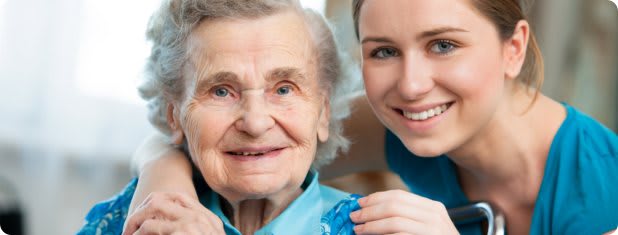 An elderly woman and a young woman smiling together.