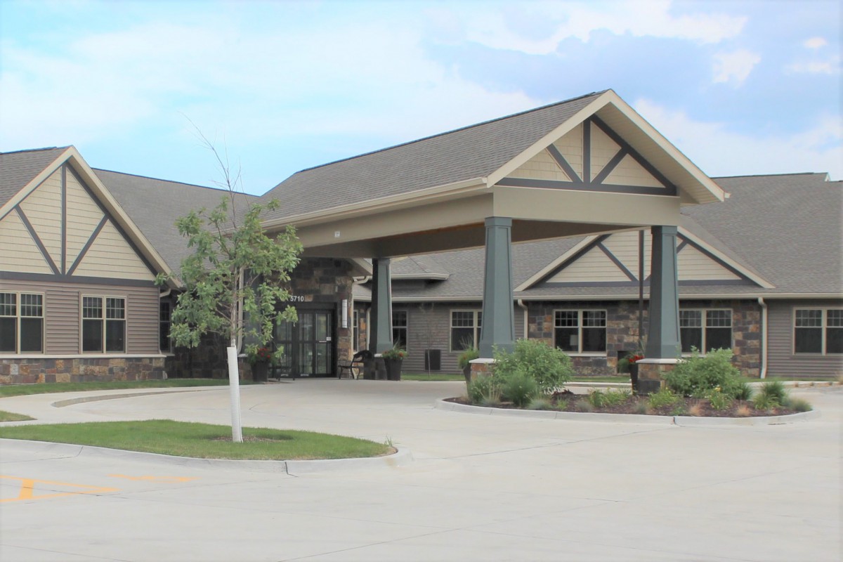 A building with a covered entrance and landscaping in front.