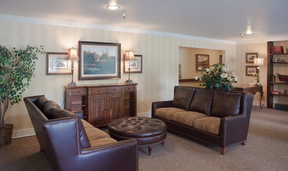 A cozy living room featuring leather sofas, a wooden coffee table, and framed artwork on the wall.