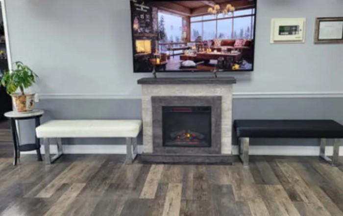 A modern waiting room with a cozy fireplace and television.