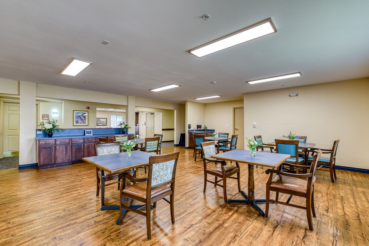 A well-lit dining area with tables and chairs arranged neatly on a wooden floor.