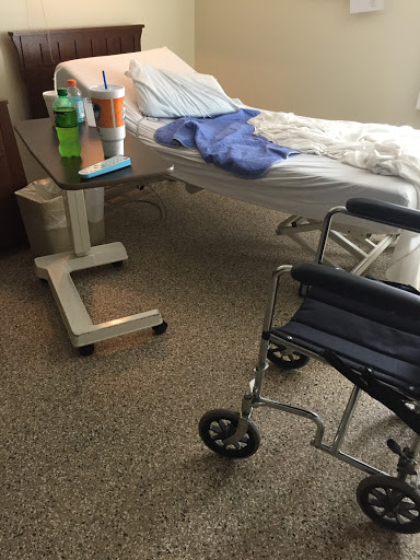 A hospital patient room featuring a bed and a wheelchair.