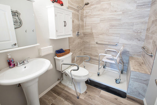 An accessible bathroom featuring a shower, toilet, and sink, equipped with safety grab bars and mobility aids.