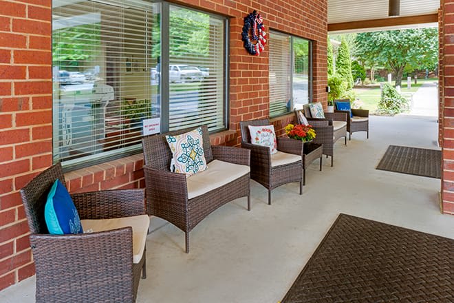 A cozy patio area with wicker chairs and colorful cushions against a brick wall.
