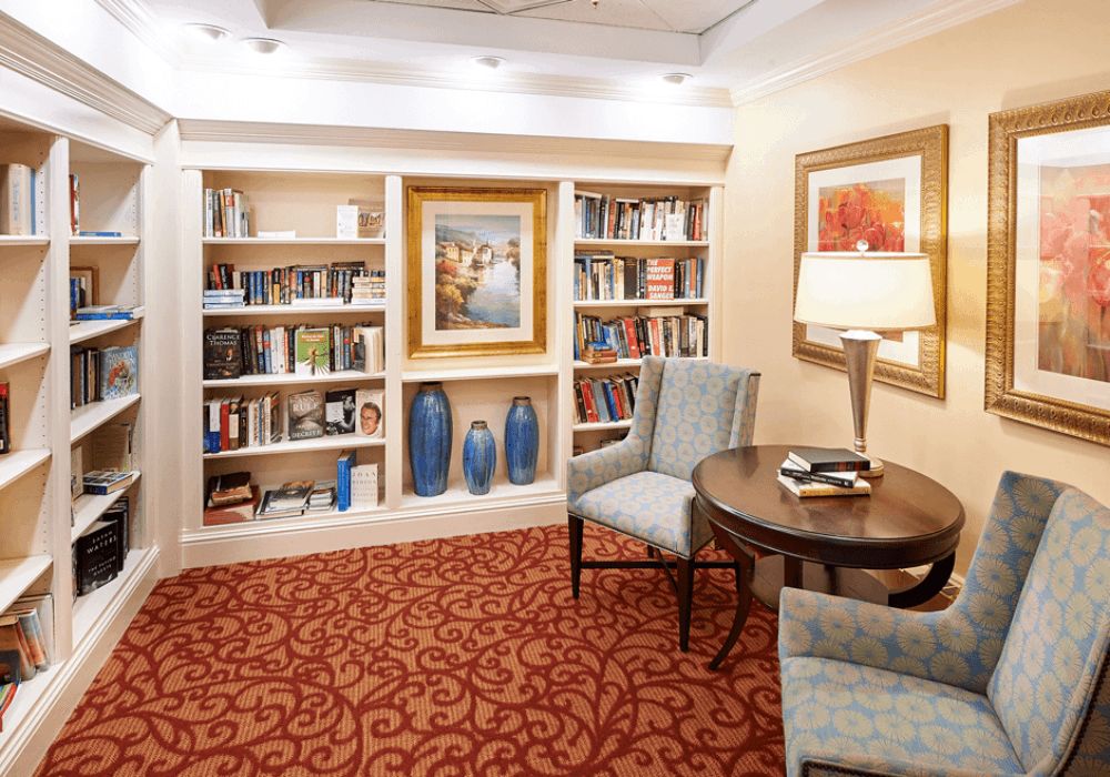 A cozy reading nook with bookshelves, artwork, and comfortable seating.