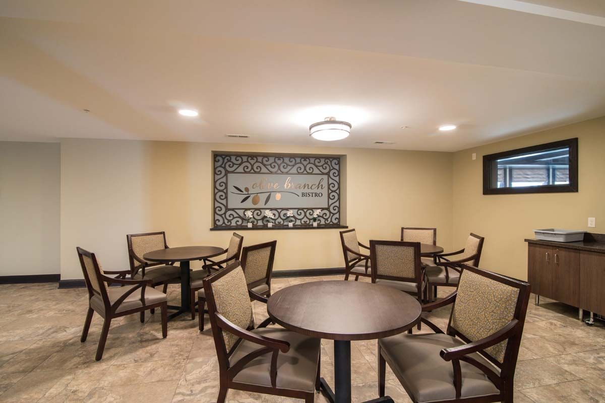A small dining area with several tables and chairs, featuring warm lighting and decorative wall art.
